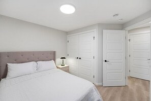 A bedroom with a bed, nightstand, and two white doors. - The Calgary Stopover (Calgary)