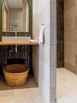 Ein Badezimmer mit Waschbecken, Spiegel, Handtuchhalter und einem Korbwäscheschrank.