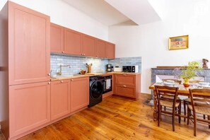 Una cucina con mobili in legno, una lavatrice, una macchina da caffè e un tavolo da pranzo con sedie.