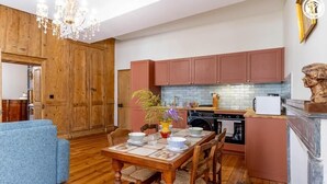 Un comedor con una mesa y sillas de madera, un sofá azul y una cocina con armarios de madera y salpicadero de azulejos.