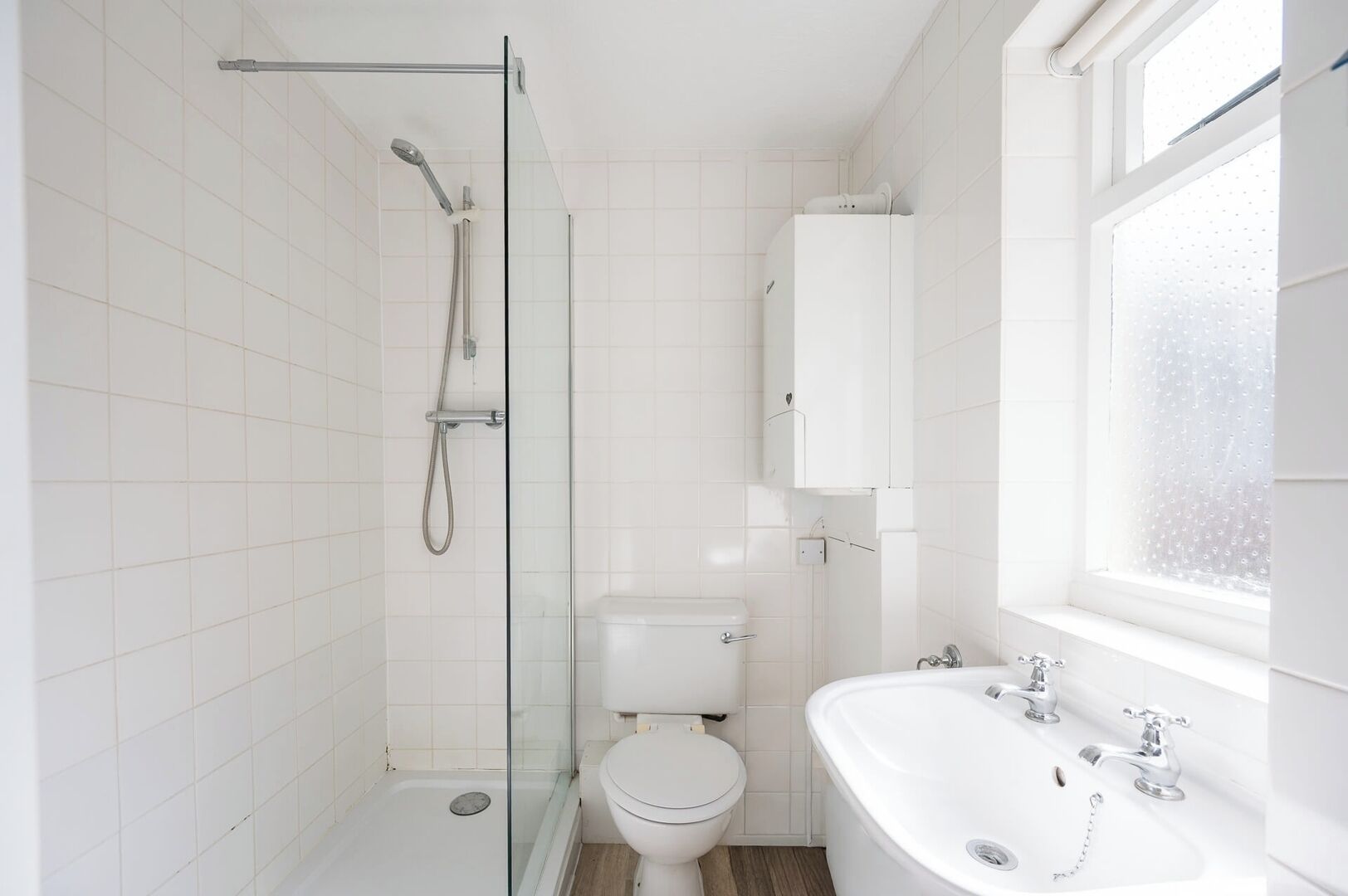 Un bagno con cabina doccia in vetro, un water, una vasca da bagno e una finestra.