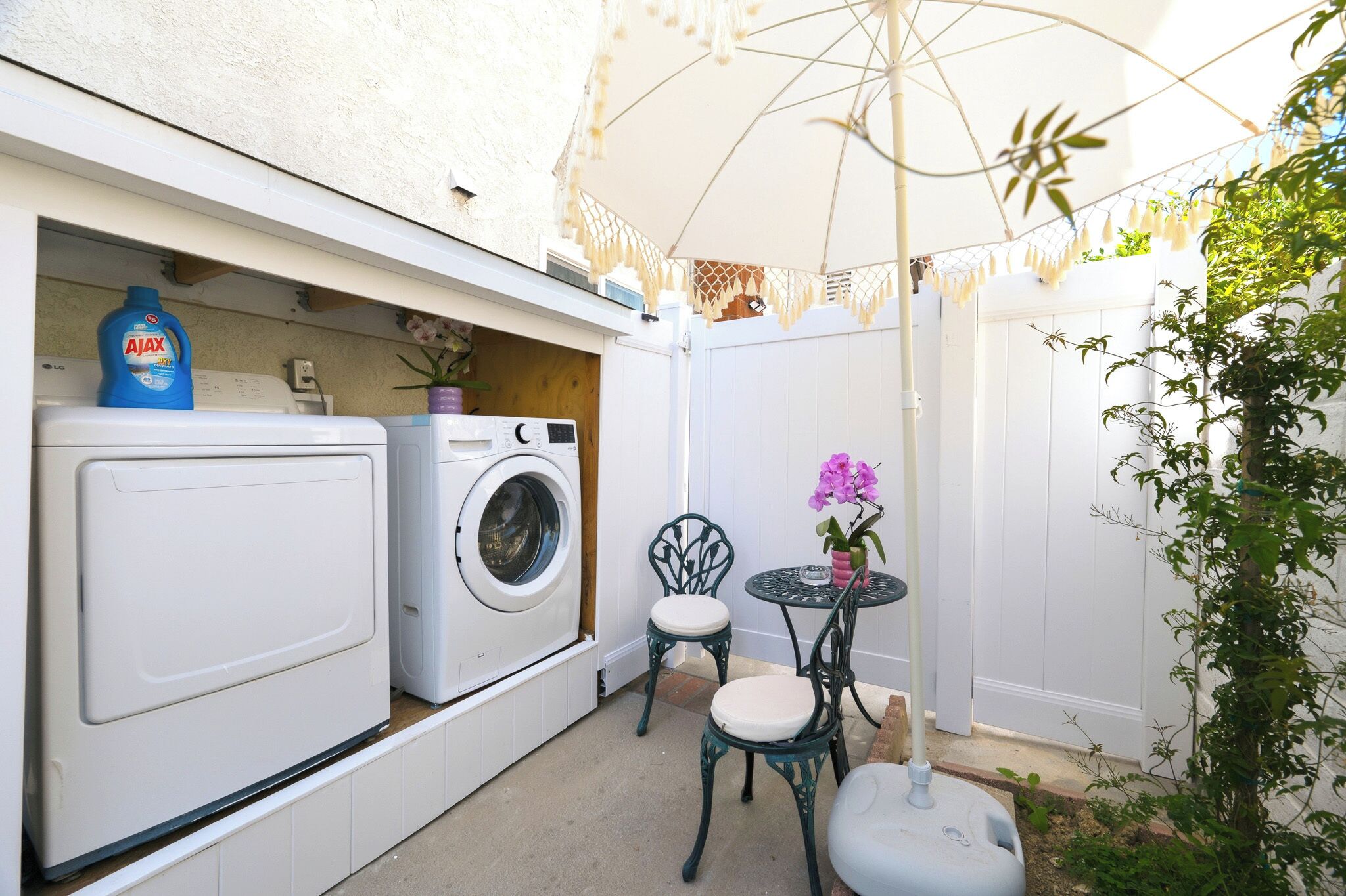 A laundry area with a washing machine and dryer, a small table with chairs, and a potted plant.