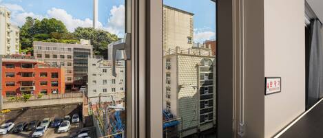 A view from inside a building looking out at a parking lot, a tower, and various buildings.