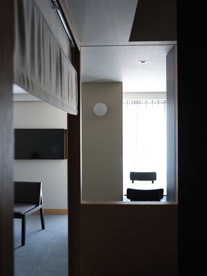Una habitación con una cama, una silla, una mesa y una ventana con cortinas.