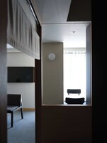 Una habitación con una cama, una silla, una mesa y una ventana con cortinas.