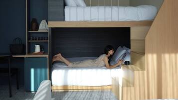 Quarto pequeno com beliche, escrivaninha e cadeira.