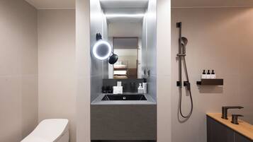A modern bathroom with a toilet, sink, and shower.