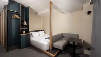 Une chambre d’hôtel moderne comprenant un lit, un coin salon et une armoire.