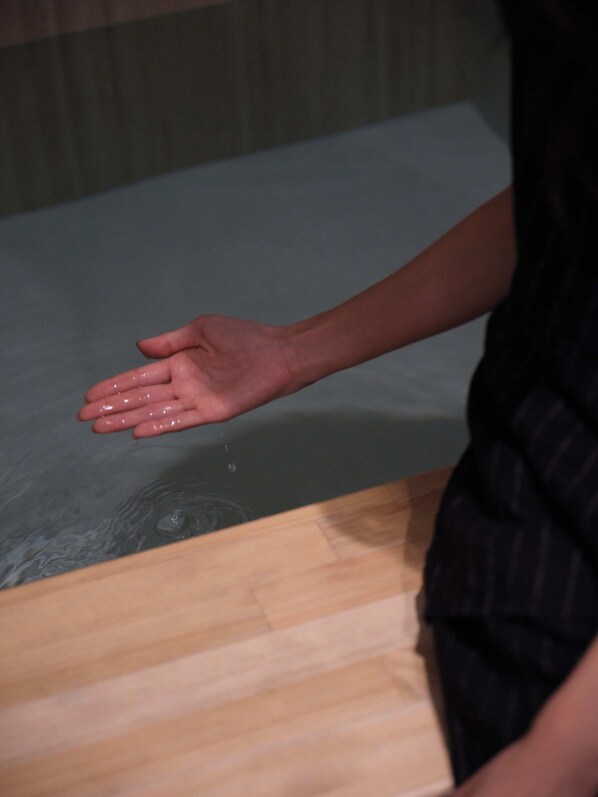A hand resting on a wooden surface with a reflective surface below.