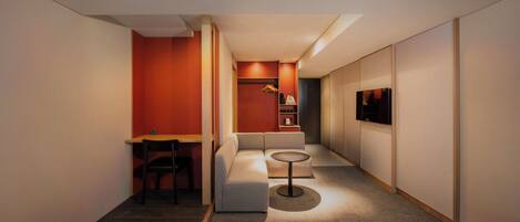 A hotel room with two beds, a desk, a sofa, a small table, and a TV.