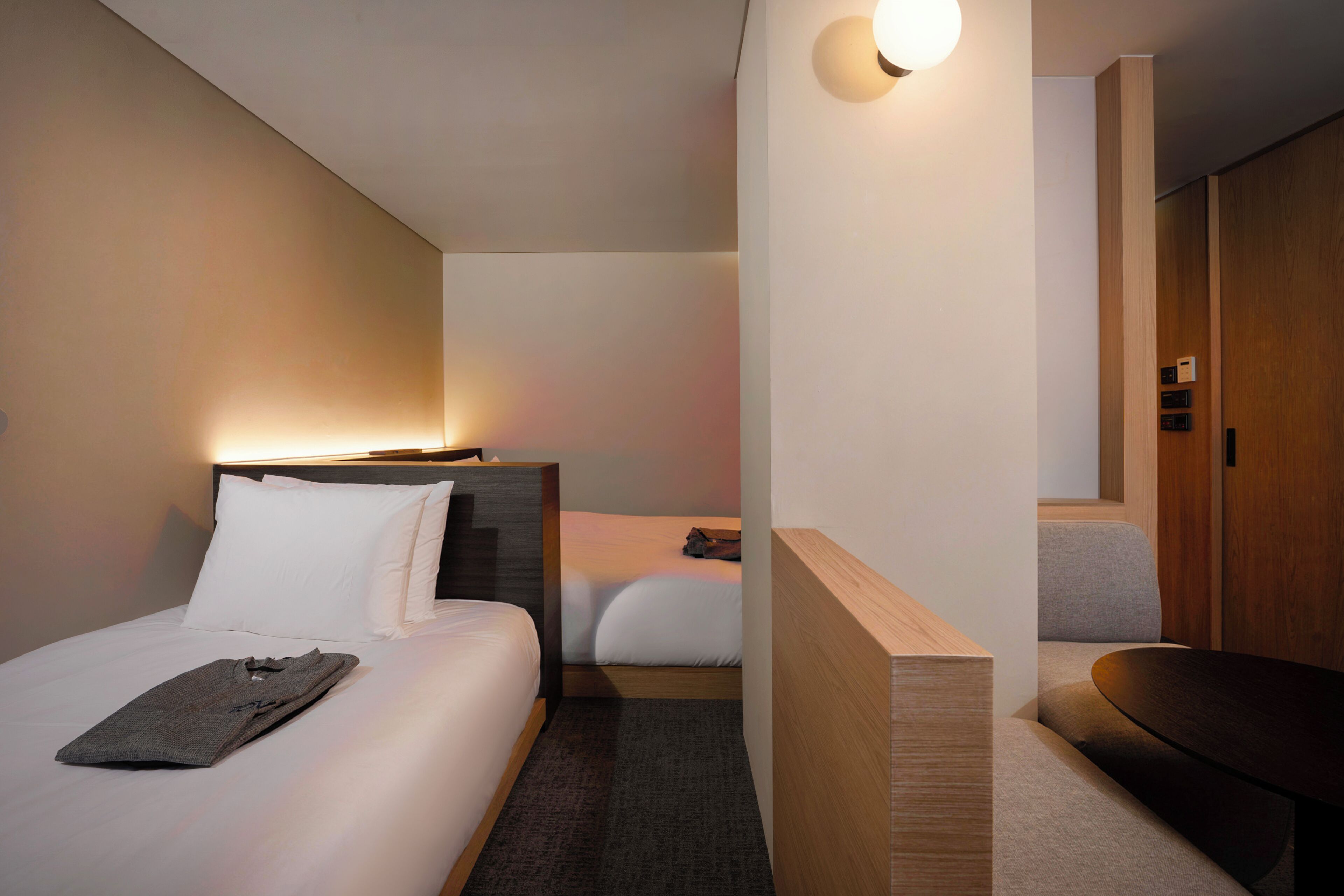 Una habitación de hotel con una cama, una mesita de noche y una lámpara de pared.