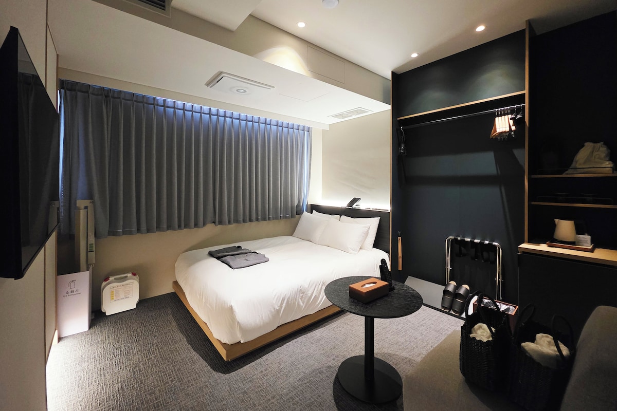 A modern hotel room with a bed, bedside table, and a built-in wardrobe.
