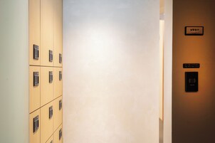 A hotel corridor with numbered lockers and a sign instructing to tap your key card.