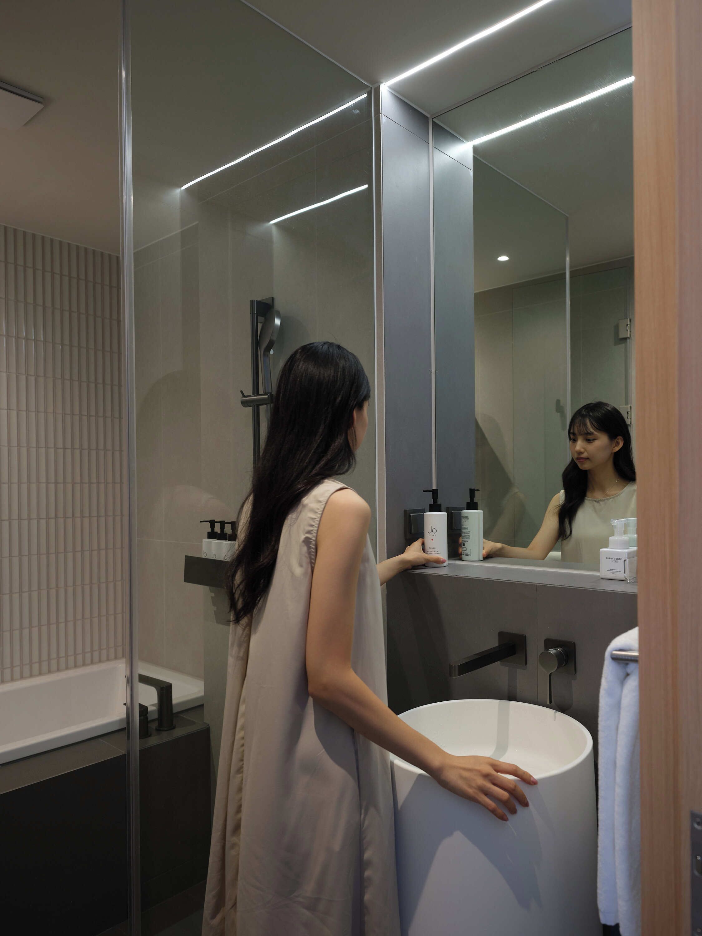 A modern bathroom with a glass shower enclosure, a white sink, and a large mirror.