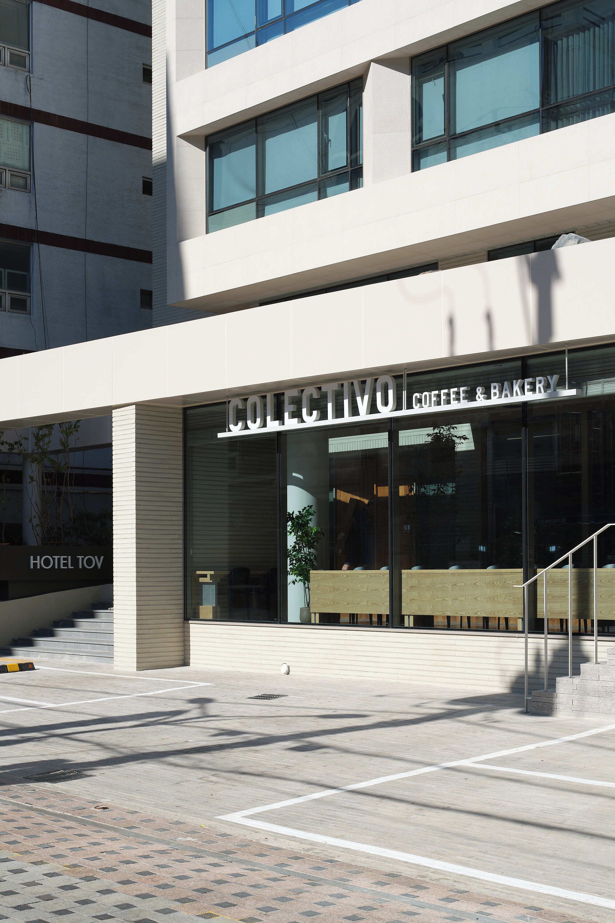 A modern building with a ground floor coffee and bakery shop, a visible staircase, and a hotel sign.