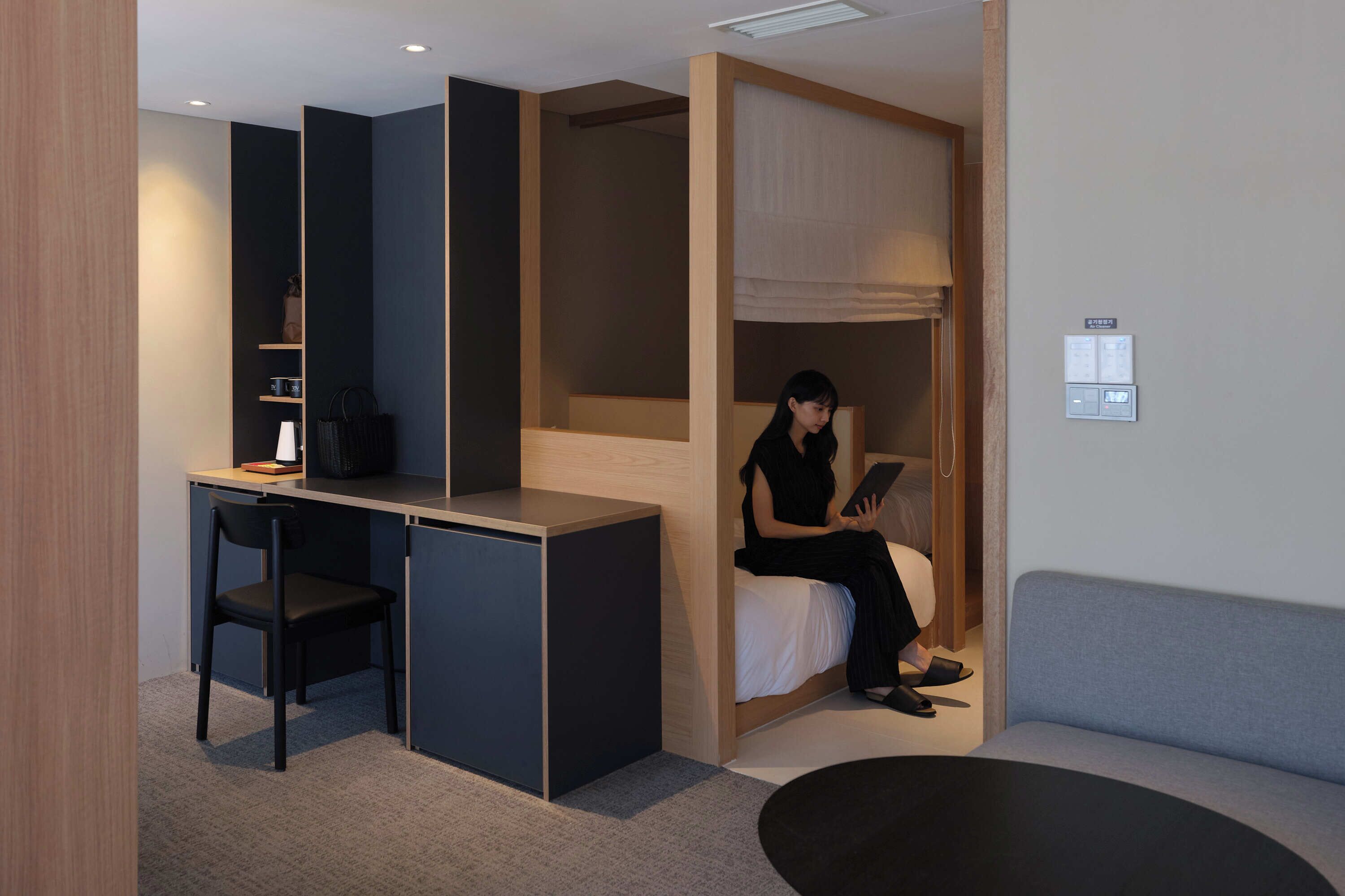 A compact hotel room with a desk, chair, bed, and a sofa.