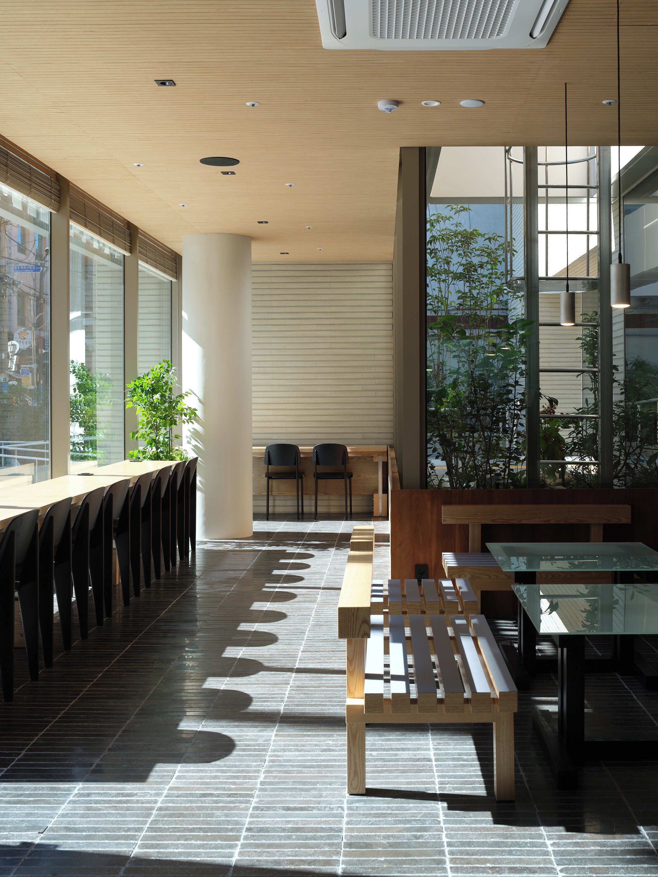 A modern interior with a long table and chairs, a bench, and a large window providing a view of the outside.