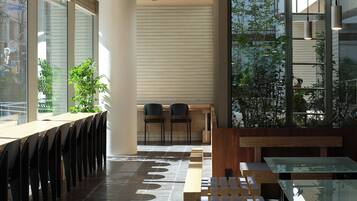 A modern interior with a long table and chairs, a bench, and a large window providing a view of the outside.