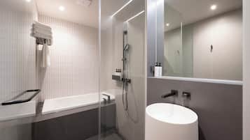 A modern bathroom with a glass-enclosed shower, a white bathtub, and a large mirror.