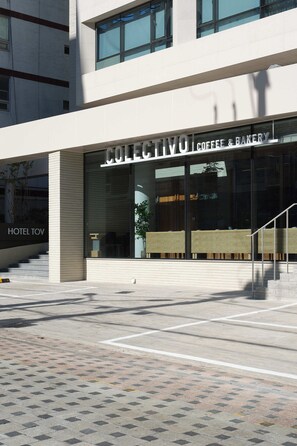 A modern building with a sign for 'COLECIVO COFFEE & BAKERY' and a visible 'HOTEL TOV' sign. - Hotel TOV (Busan)