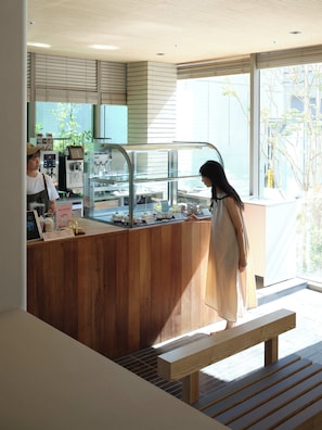 A cafe with a wooden counter, a cash register, and a menu board. - Hotel TOV (Busan)
