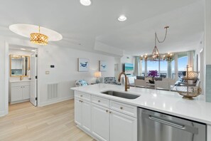 Una cocina moderna con una isla central, armarios blancos y un ventanal con vistas.