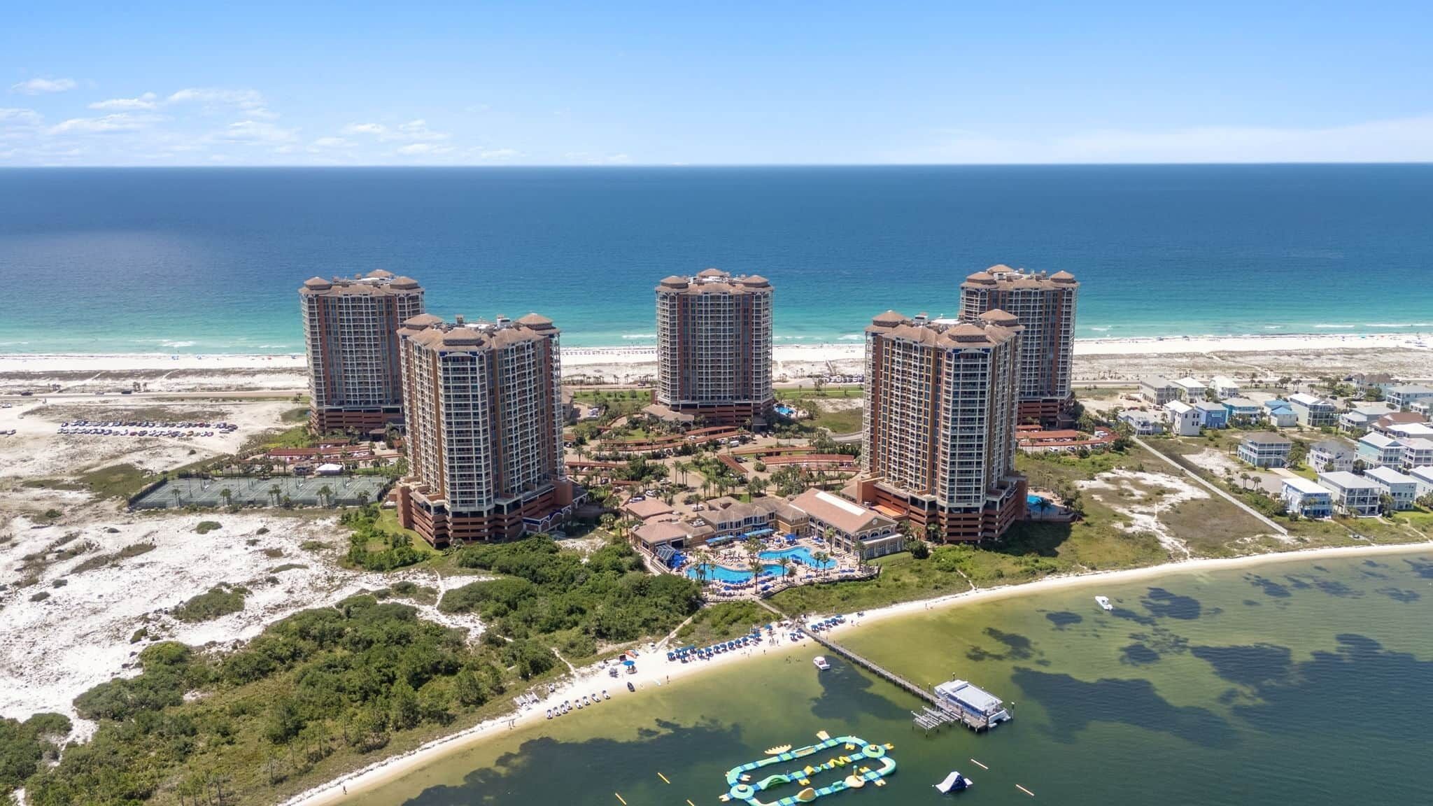 Un complejo hotelero frente al mar con varios edificios altos, una playa y una zona de piscina.