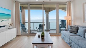 En moderne stue med balkon, loftventilator, fladskærms-tv og havudsigt.
