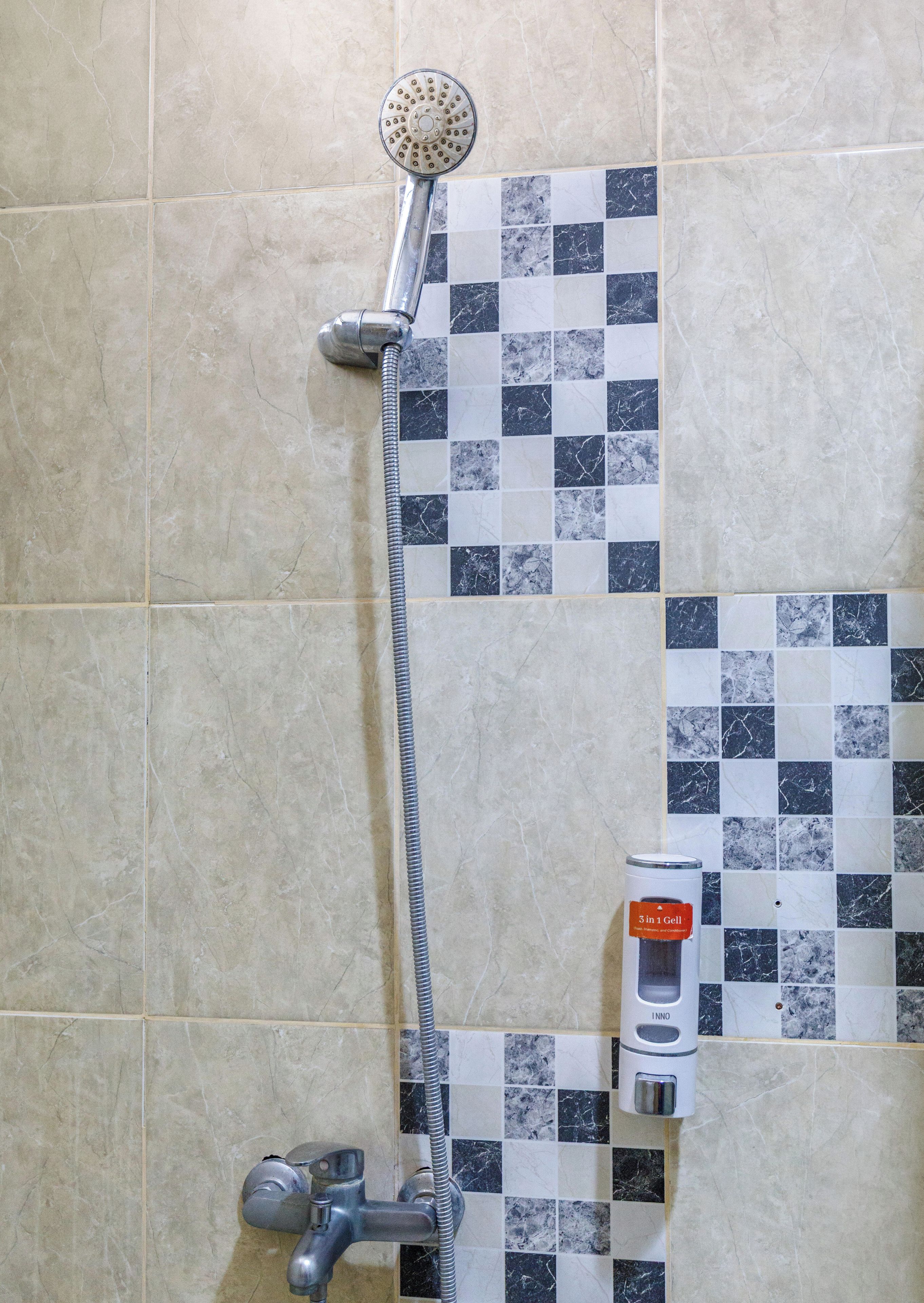 A shower with a handheld showerhead and a handheld water pump.