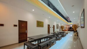 Un espacio interior amplio con varias mesas y bancos, una escalera y un techo alto.