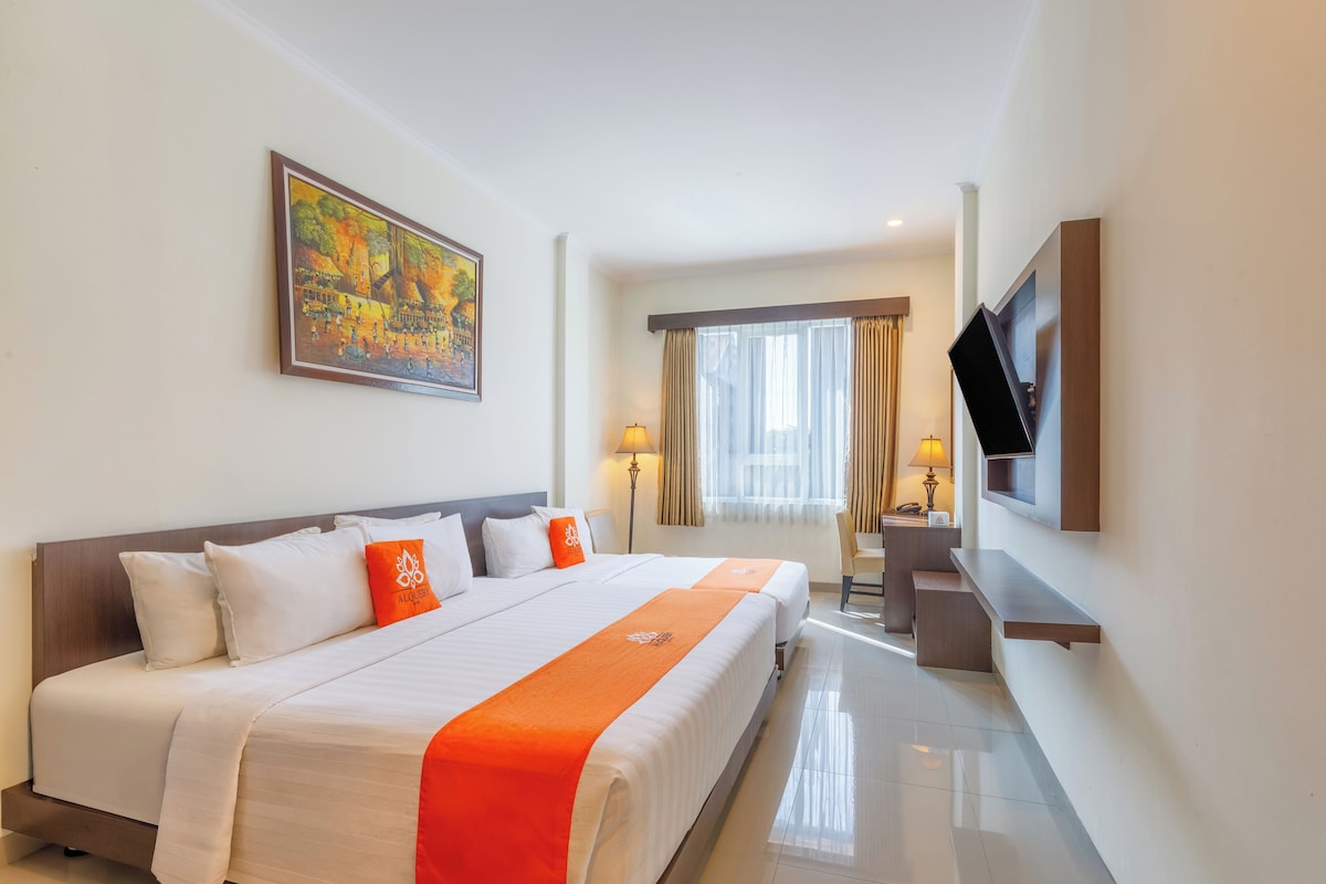 A hotel room with a large bed, a TV mounted on the wall, and a painting above the bed.