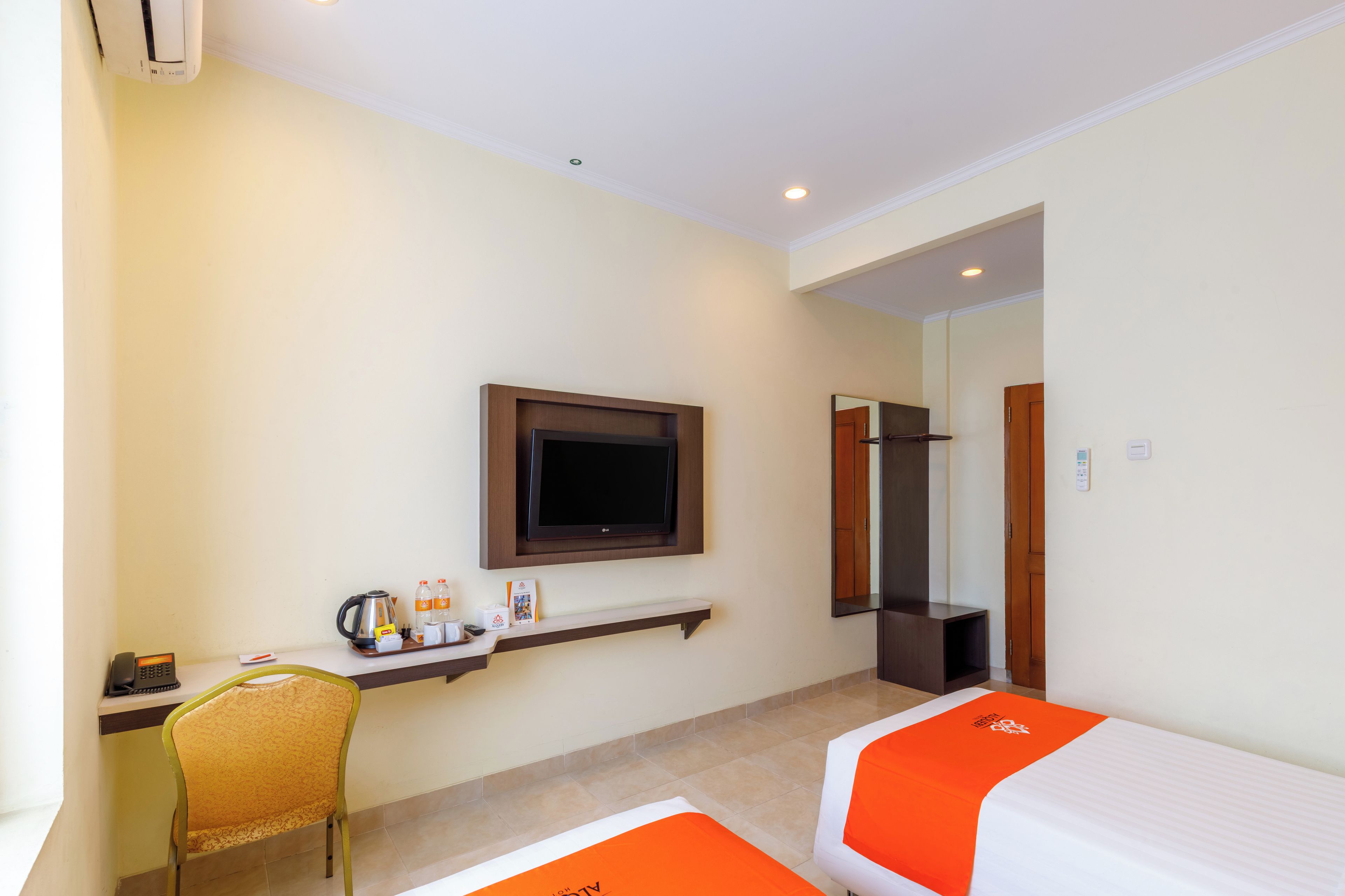 A hotel room with a bed, a desk with a chair, a television, and a bathroom door.