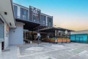 Un hotel moderno con un área de estar exterior cubierta y una entrada visible.