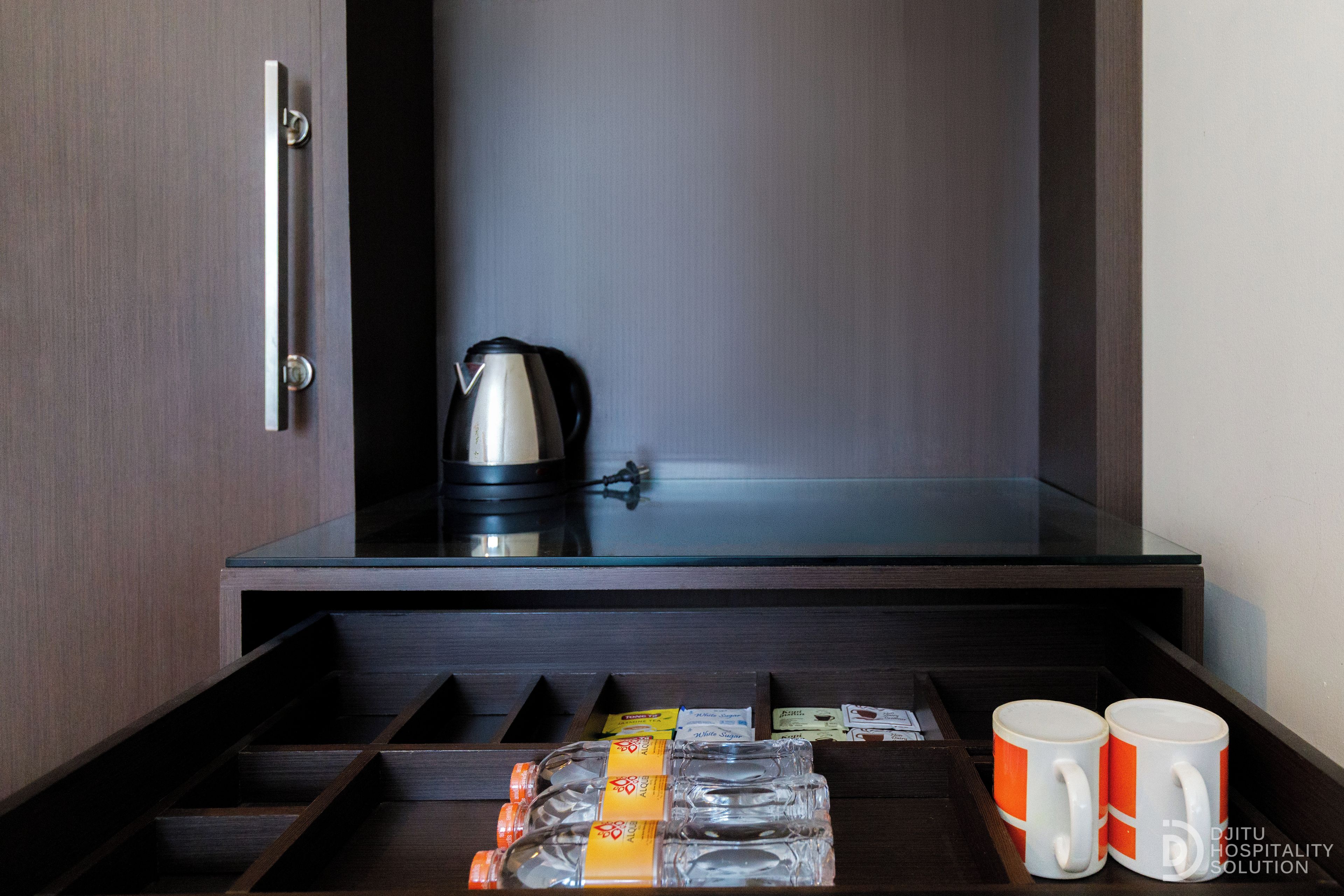 A hotel room with a minibar, a kettle, and two mugs.