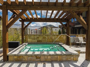 Eine Pergola aus Holz mit einer Steinwand und einem Poolbereich.
