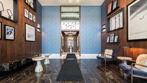 Eine Lobby mit Marmorboden, gerahmten Kunstwerken und Sitzbereichen.
