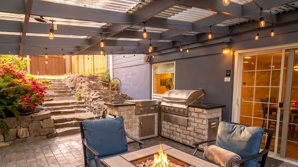 Un patio al aire libre con una parrilla de piedra, asientos y un pozo de fuego.