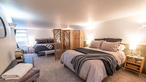 Un dormitorio con una cama grande, una mesita de noche con lámpara, un calefactor y una ventana con cortinas.