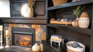 Una chimenea con detalles de piedra, un reloj y objetos decorativos en estantes.