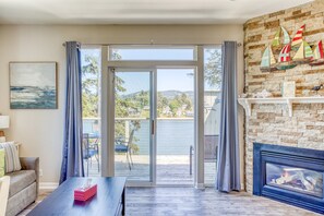 Ein Wohnzimmer mit Kamin, Meerblick und einem Balkon mit Sitzmöbeln.