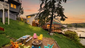 A lakeside property with a deck, outdoor seating, and a fire pit.
