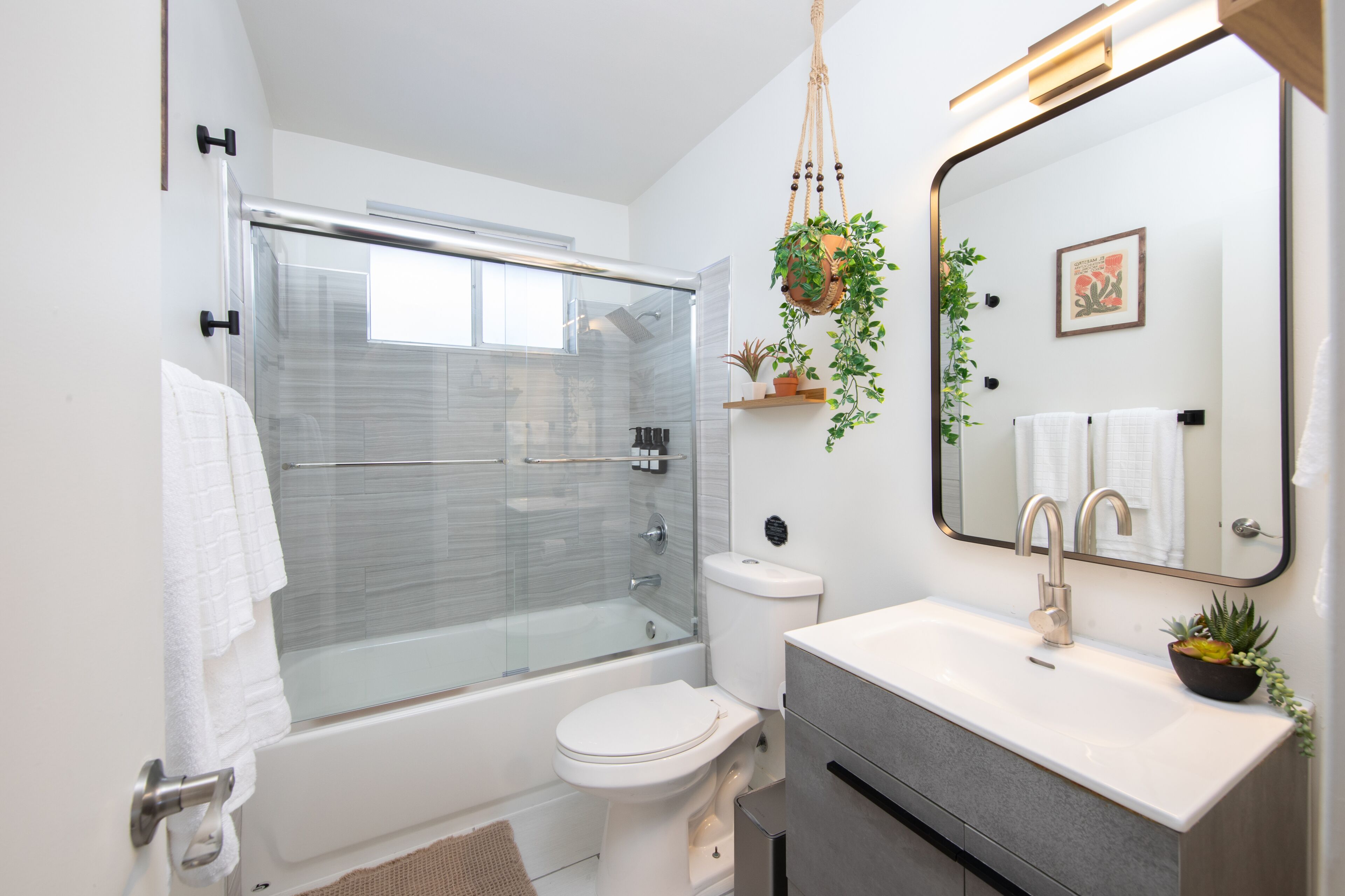 A modern bathroom with a glass-enclosed shower, a toilet, a sink, and a mirror.