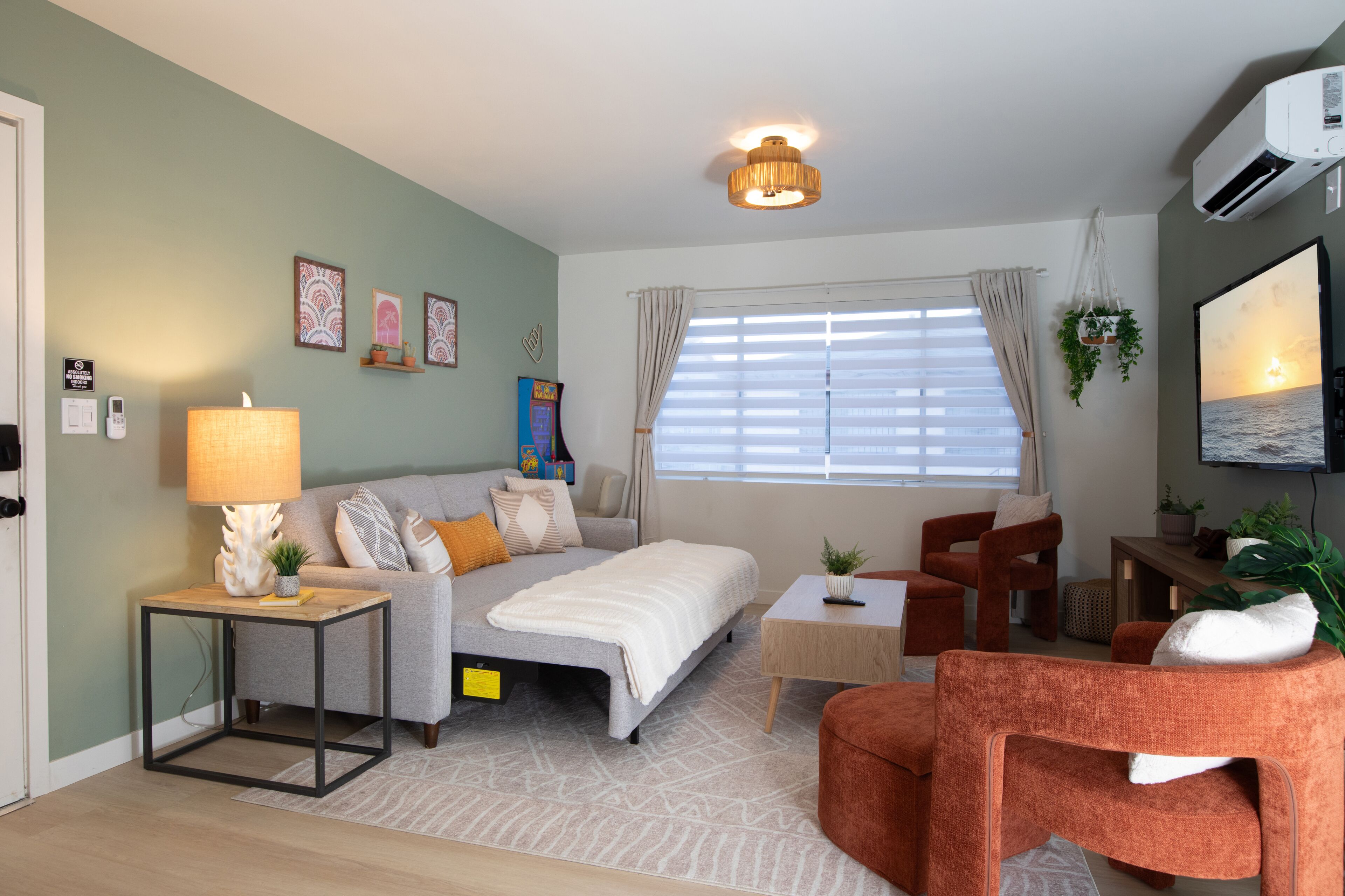 A modern living room with a sofa, a coffee table, a TV, and a window with blinds.