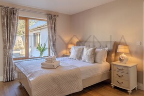 A bedroom with a bed, bedside tables, a window with curtains, and a view of the outside.