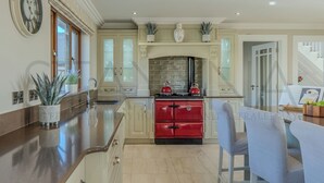 Une cuisine dotée d’un îlot central, d’une cuisinière rouge et d’un coin repas avec des chaises.