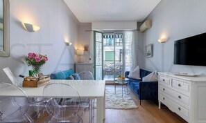 Ein modernes Wohnzimmer mit Essbereich, einer Couch, einem Fernseher und Blick ins Freie.