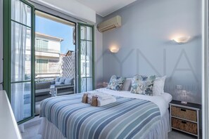 Ein Schlafzimmer mit Bett, Kissen, Nachttisch, Fenster und Klimaanlage.