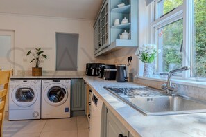 Cocina compacta con lavadora, cafetera y lavabo.