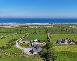 An aerial view of a rural area with fields, a winding road, and a few buildings.