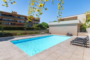 A swimming pool with lounge chairs and a building with balconies in the background. - Bellevue Flora 2 bedroom apartment (Antibes)